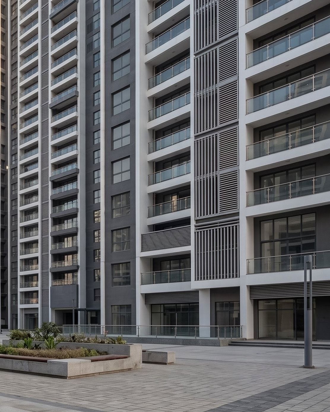 Close view of apartment balconies with glass railings above a planted courtyard.